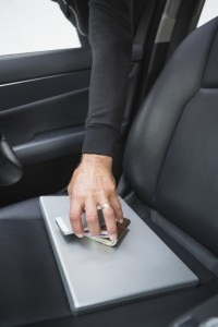 Arm reaching through car window to grab phone, wallet, and laptop