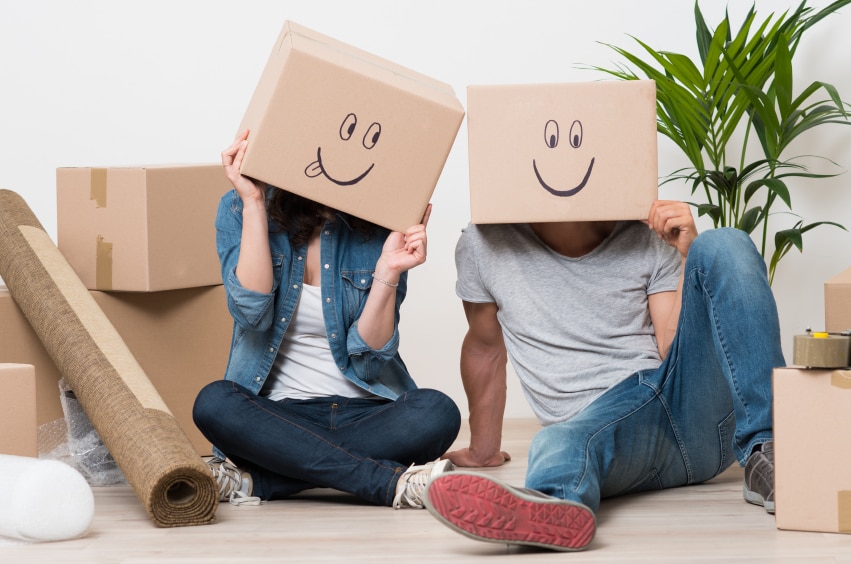 two people sitting on the floor with cardboard boxes with smiley faces drawn on them over the people's heads