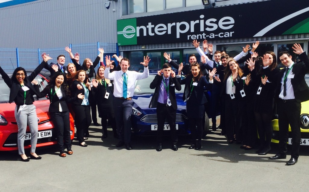 Enterprise Interns with their hands in the air outside of a rental building